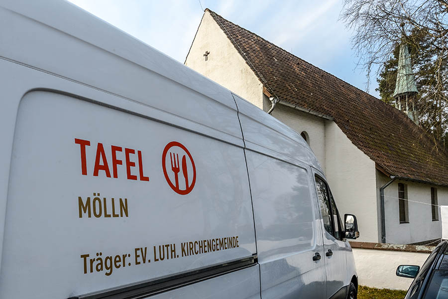 Ein Transporter mit der Aufschrift "Tafel Mölln" parkt vor einer Kirche