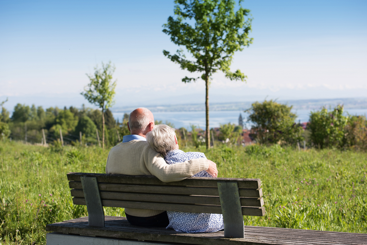 Älteres paar auf einer Bank über dem Bodensee sitzend