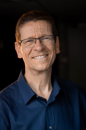 Mann im schwarzem Hemd mit Brille