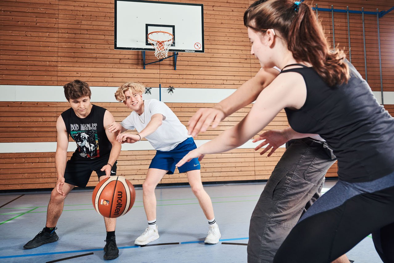 Schüler*innen spielen Basketball im Sportunterricht
