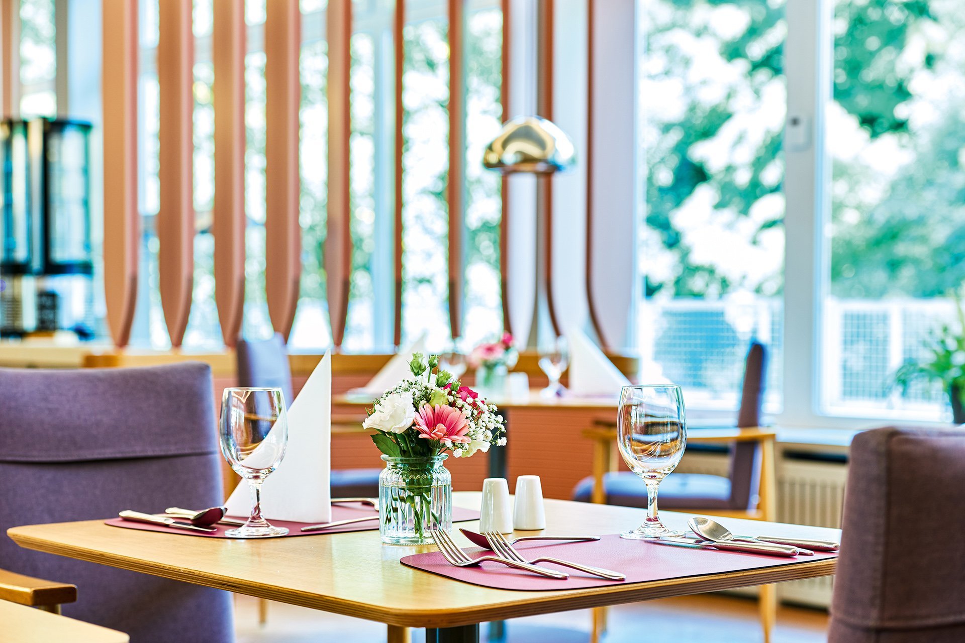 Nahaufnahme eines gedeckten Tisches mit Blumen-Dekoration im Restaurant des Augustinum Kassel