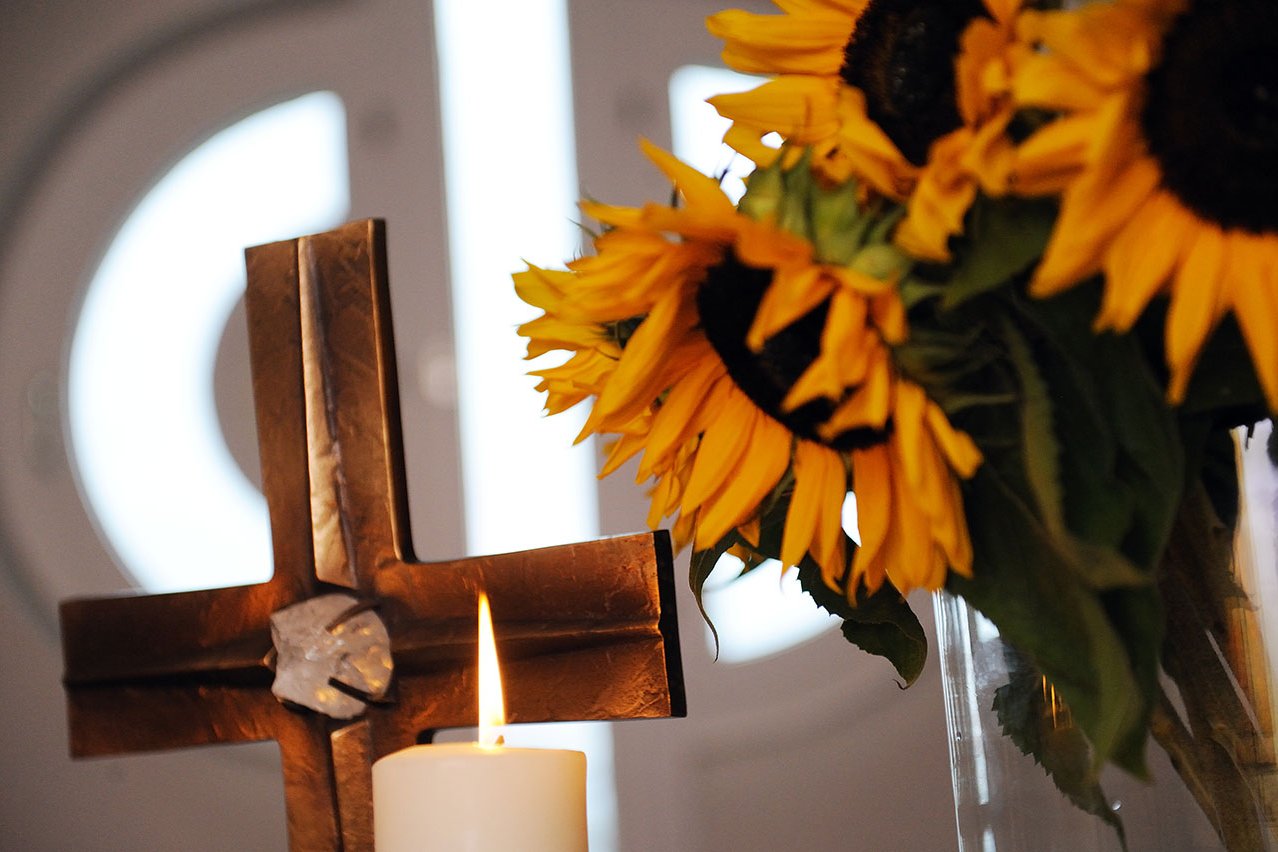 Kreuz, Kerze und ein Strauß Sonnenblumen