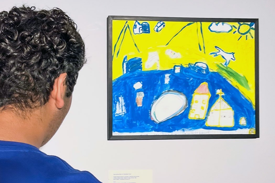 ein junger Mensch schaut sich ein buntes Bild in einer Ausstellung an