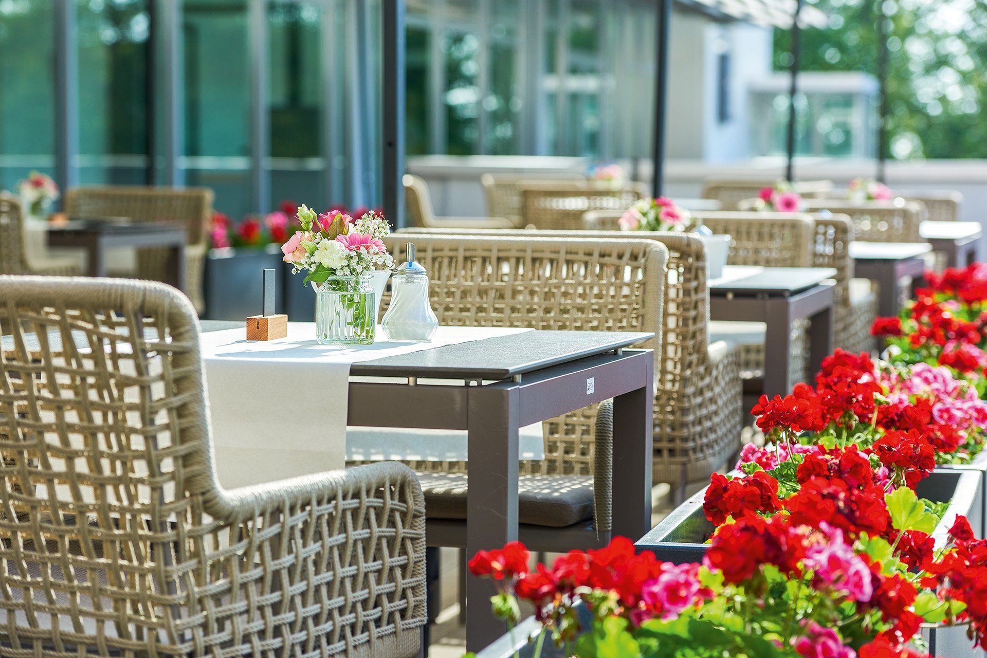 Kleine gedeckte Tische auf einer Terrasse mit Blumen-Dekoration