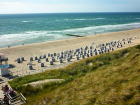 Blick auf einen Strand mit Strandkörben und Dünenausläufern