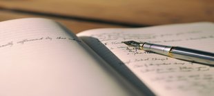 Stift und aufgeschlagenes Notizbuch