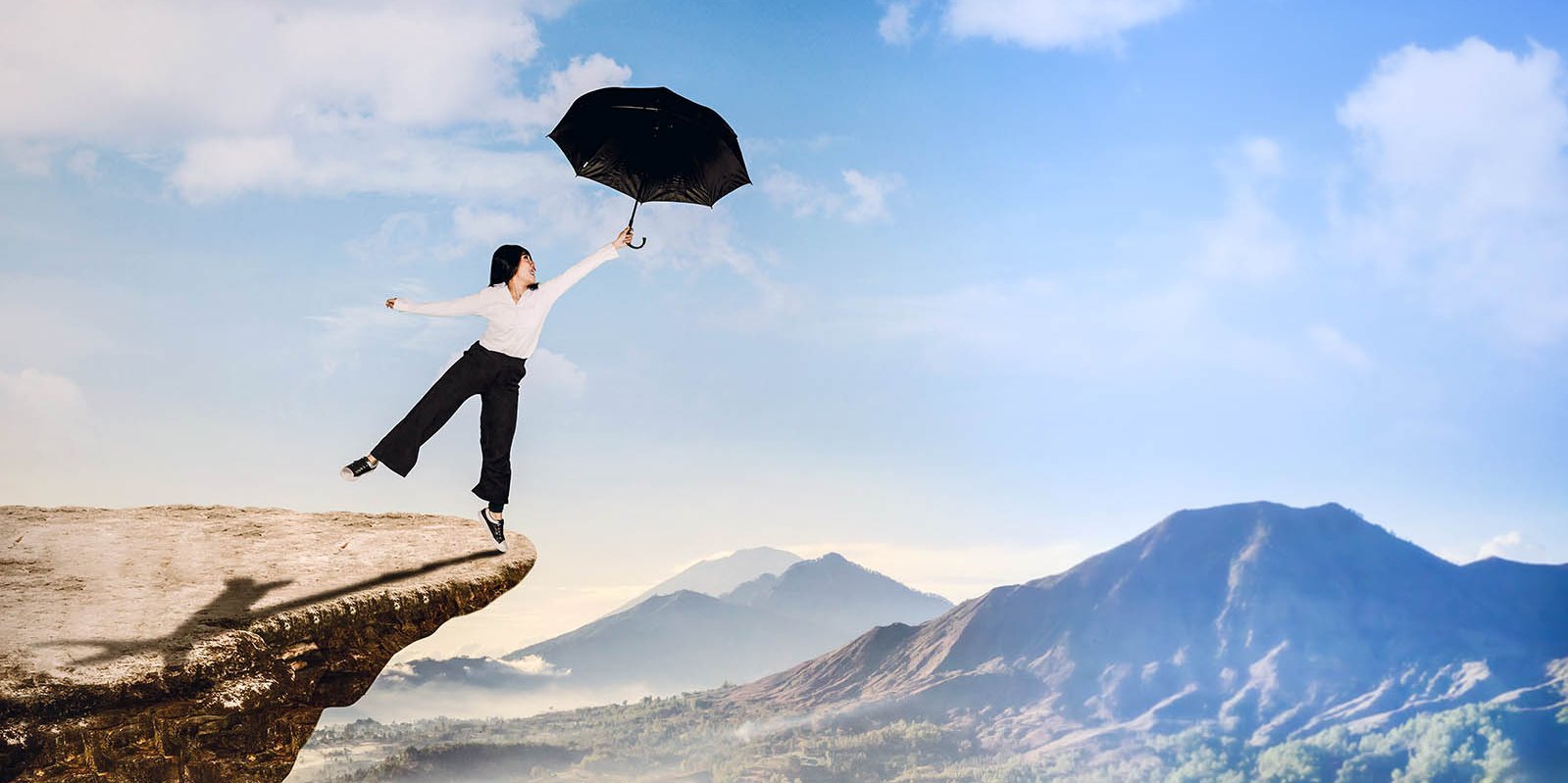 Frau mit Regenschirm über einem Abgrund