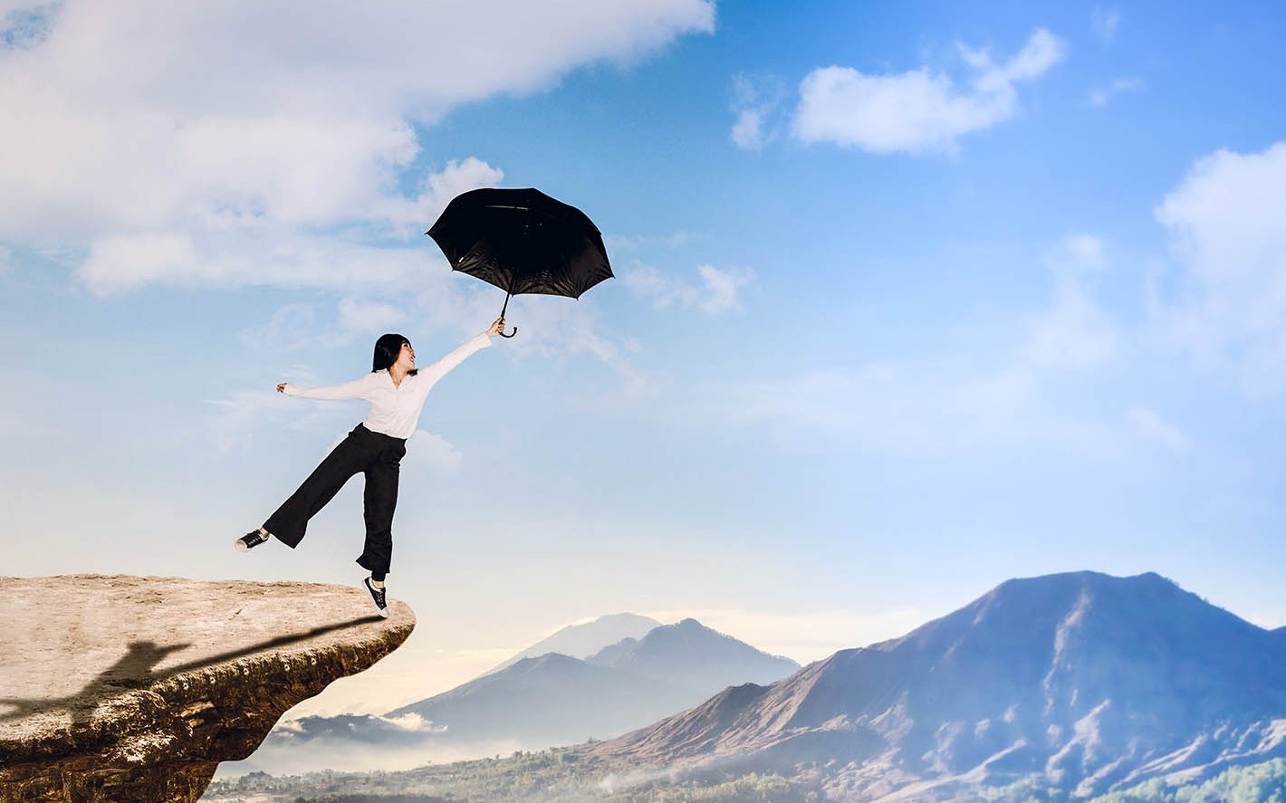Frau mit Regenschirm über einem Abgrund