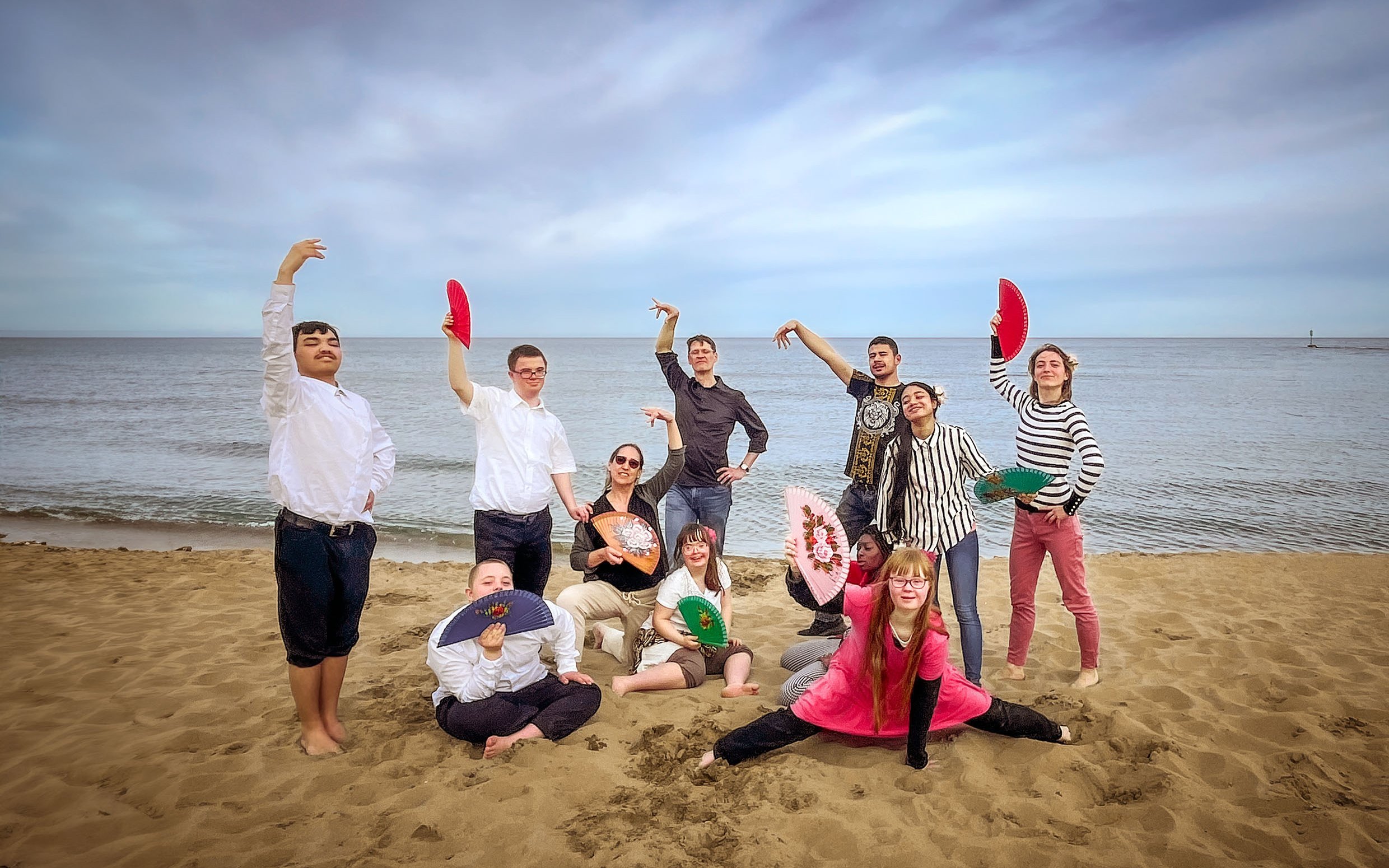 Schülerinnen und Schüler mit Lehrerinnen mit Fächern am Strand 