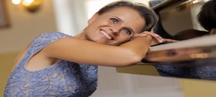 Frau in einem hellblauen Kleid lehnt an einem Klavier