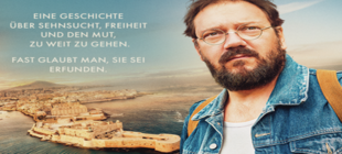 Bärtiger Mann mit Brille blickt geradeaus hinter ihm die Umrisse einer Stadt am Meer