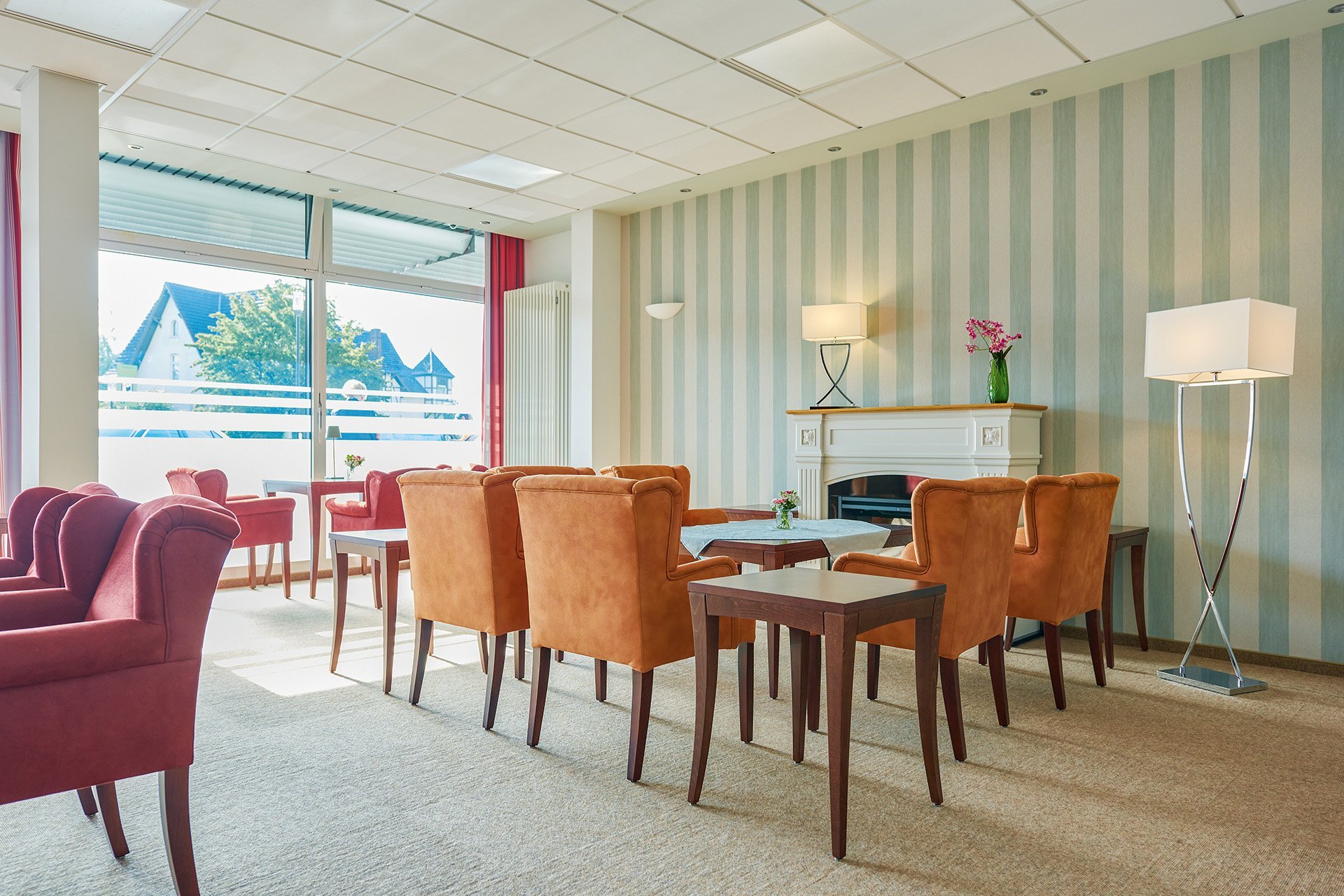 Tische umgeben von bequemen Sitzmöglichkeiten stehen in einem hellen Raum 