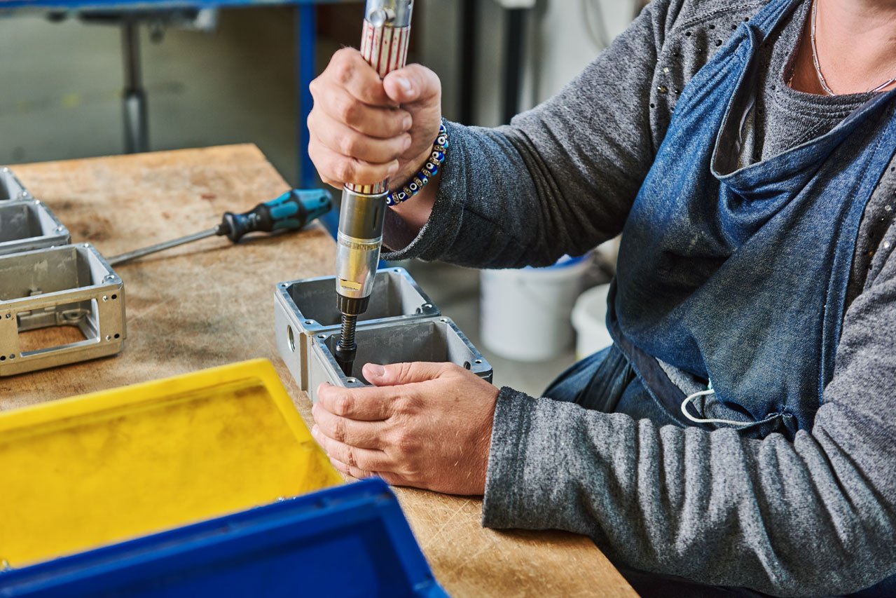 Eine Klient*in montiert eine Schraube an einem Metallteil