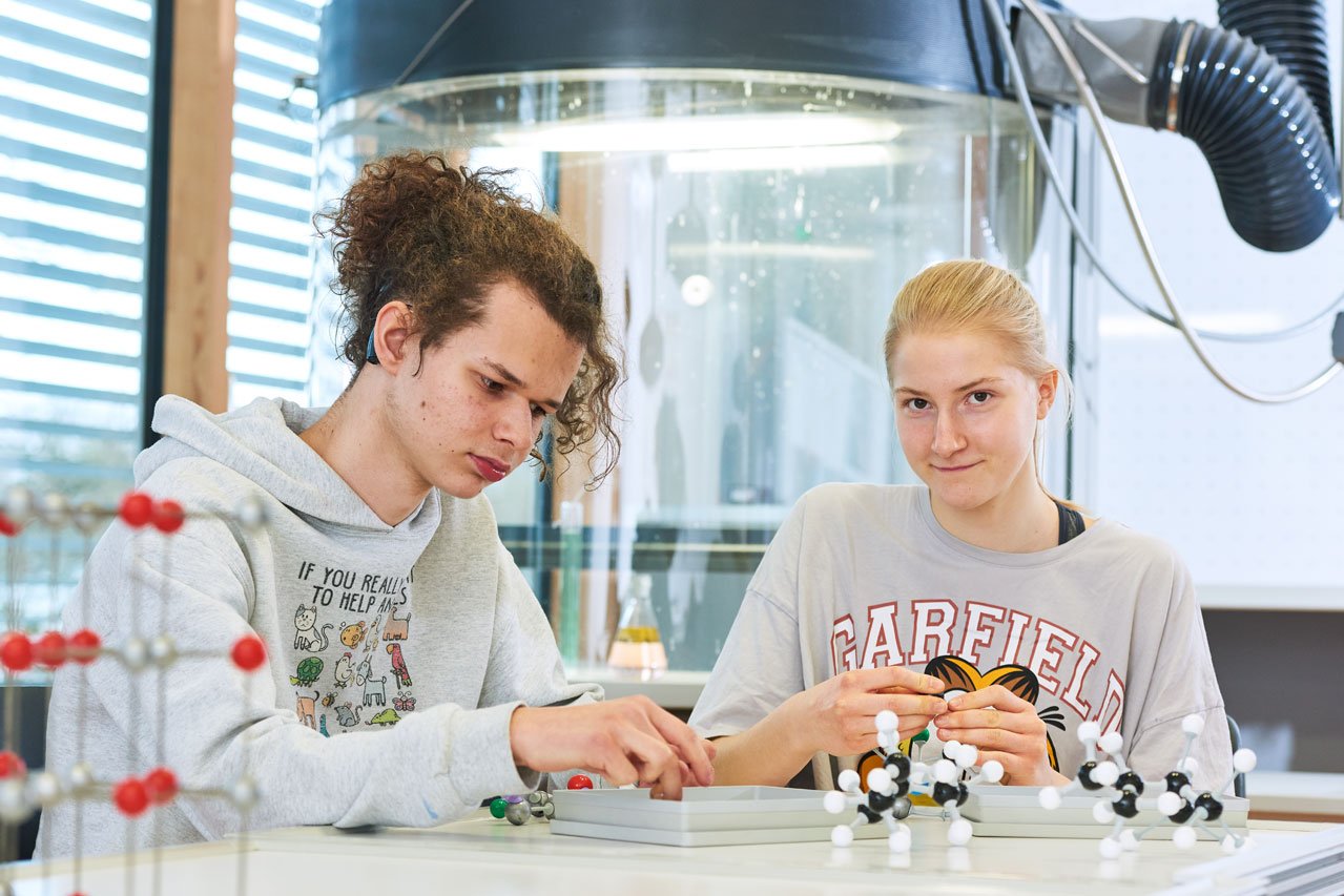 Zwei Schüler*innen bauen im Chemieunterricht Molekülmodelle zusammen 