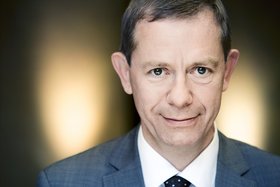 Mann in Anzug, weißem Hemd und Krawatte vor Gegenlicht