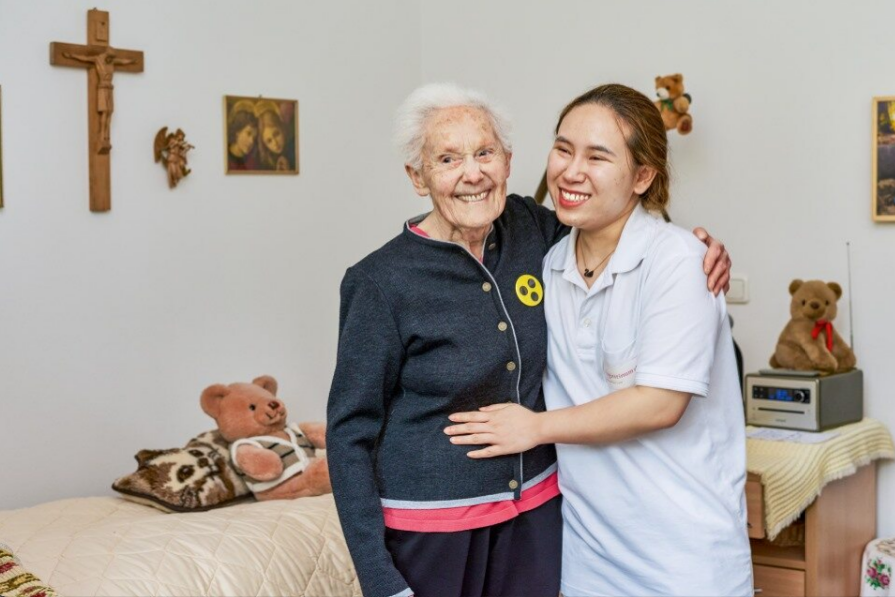 Augustinum Berchtesgadener Land Stationsaere Pflege Eine Seniorin und eine Mitarbeiterin umarmen sich und lächeln