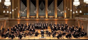 Johann Sebastian Bach: Matthäuspassion Ein Chor und ein Orchester geben ein Konzert auf einer großen Bühne.