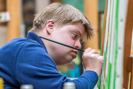 Künstler mit Down-Syndrom malt auf eine Leinwand