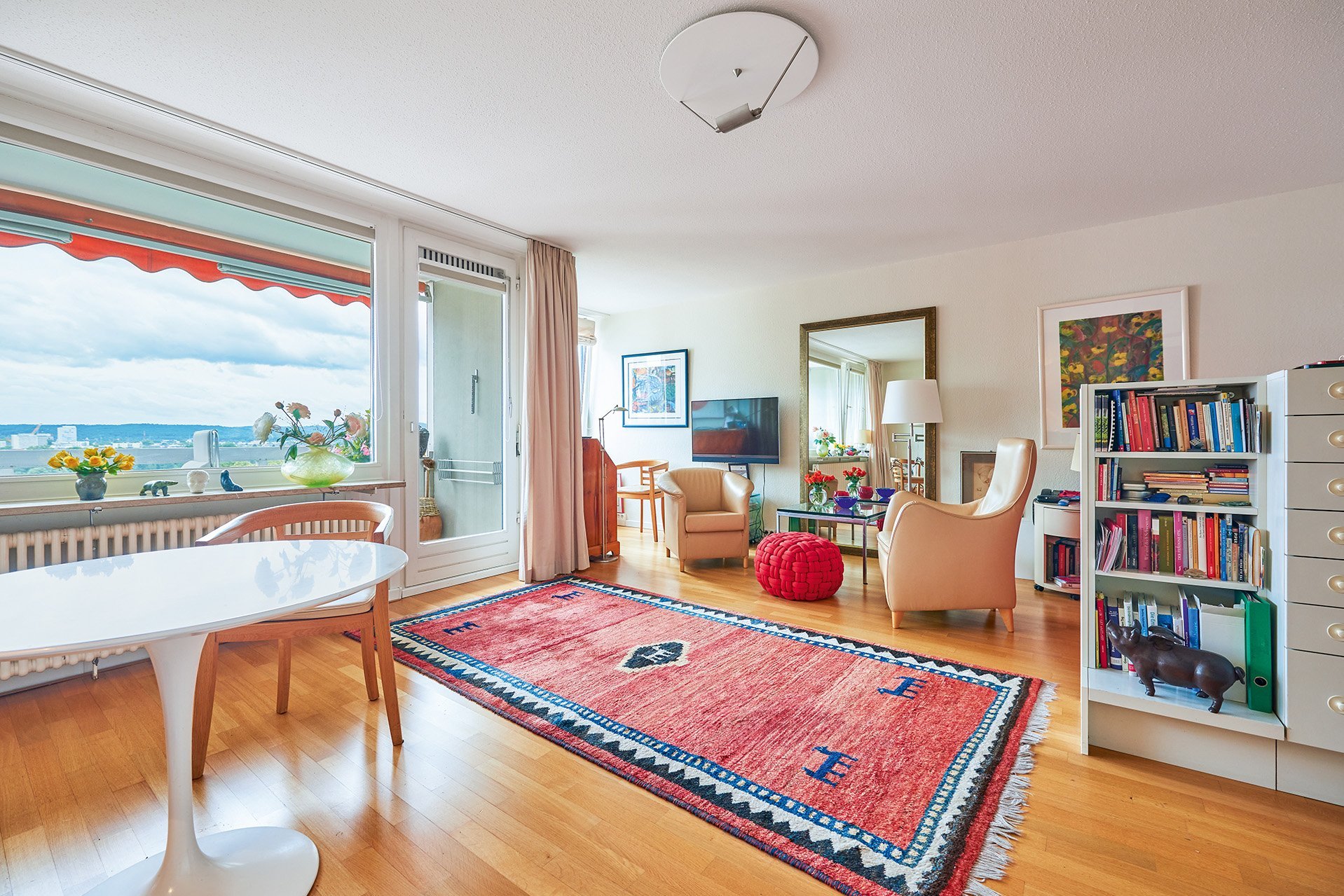 Ein großräumiger Wohnbereich mit zwei Sesseln, einem Esstisch und einem Bücherregal