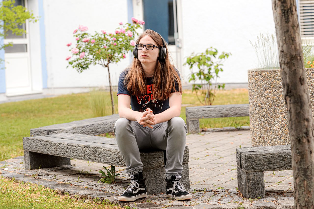 Ein Jugendlicher sitzt im Garten des Augustinum Studienheims