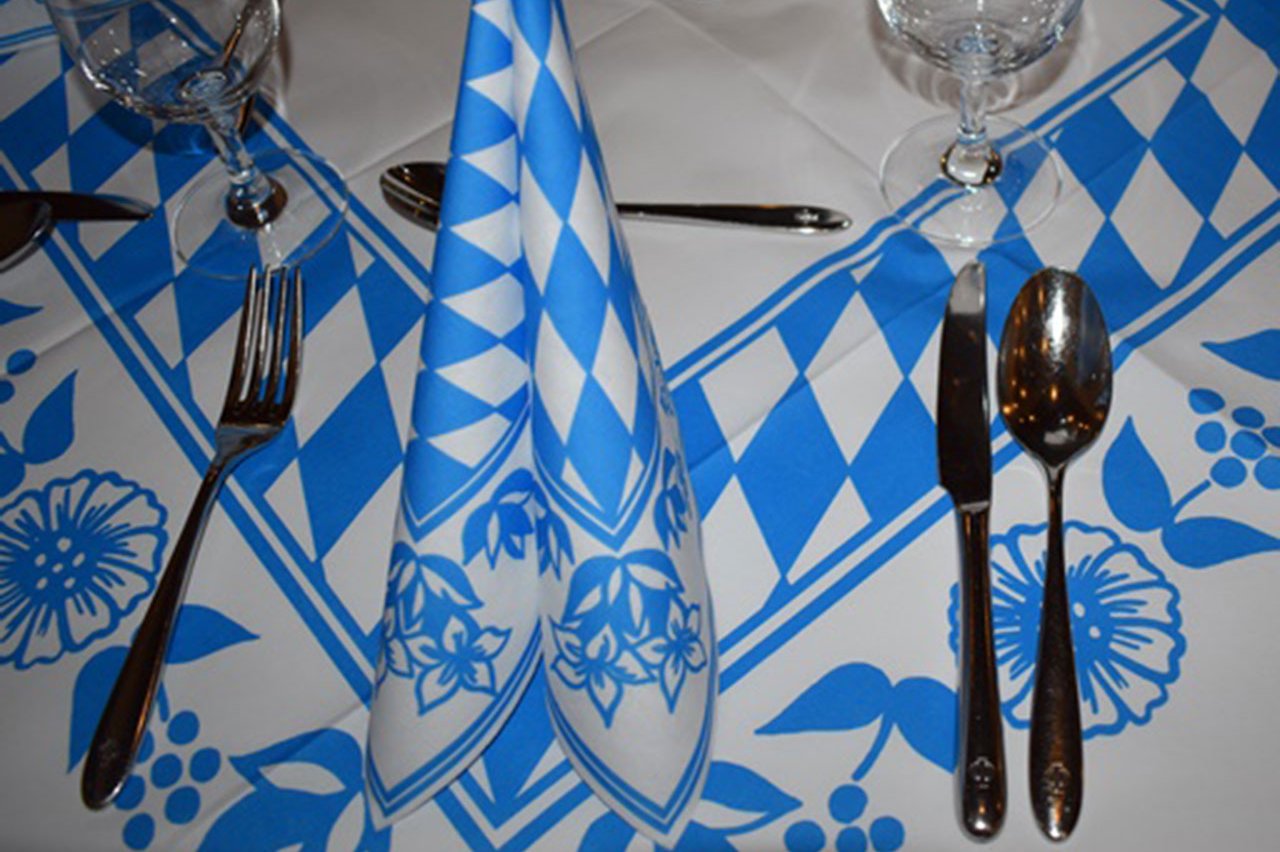 Gedeckter Tisch mit Servietten und Tischdecke in weißblauem Muster