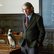 Ein mittelalter Mann, neben ihm sitzt ein Pinguin auf dem Tisch