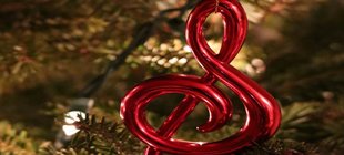 Notenschlüssel und Christbaumkugel vor Tannenzweigen