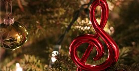 Notenschlüssel und Christbaumkugel vor Tannenzweigen