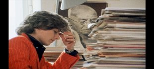 Petra Kelly mit Akten und Ghandi-Bild im Hintergrund