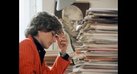 Petra Kelly mit Akten und Ghandi-Bild im Hintergrund