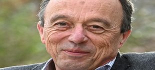 Alter 4.0 – schöne neue Welt? Portraitaufnahme eines älteren Mannes mit dunkeln Haaren vor einem unscharfen Hintergrund.