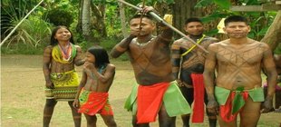 Kinder und Jugendliche eines Indianervolks aus Amazonien mit traditioneller Kleidung und bemalten Oberkörpern und Gesichtern stehen draußen.
