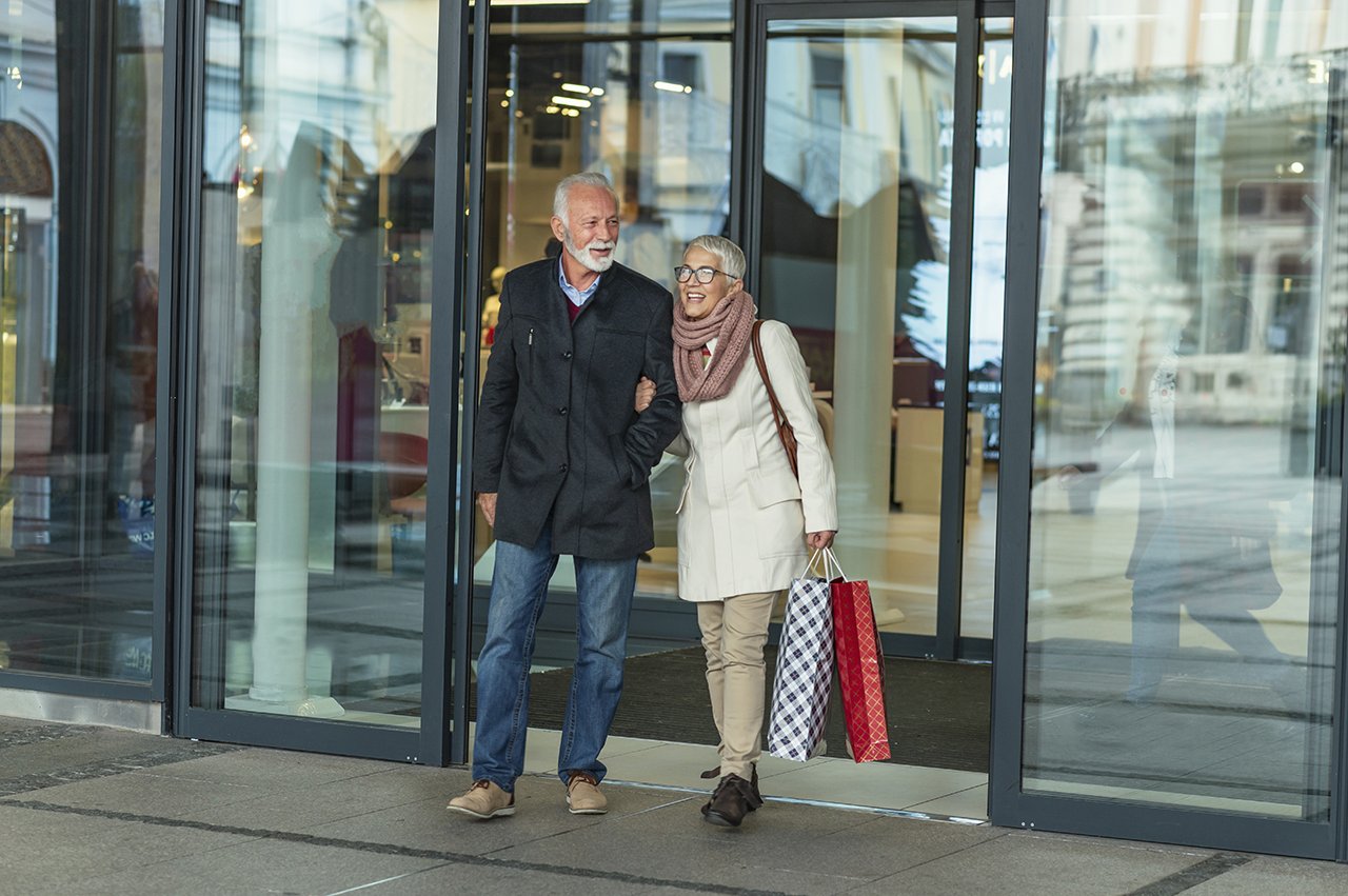 Seniorenpaar am Eingang eines Einkaufszentrums