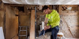 Ein junger Mann bearbeitet einen Holzbalken