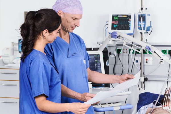 Arzt und Gesundheits- und Krankenpflegerin kontrollieren das EKG eines Patienten