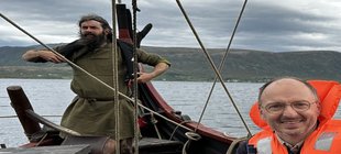 Mann mit Brille in einer Rettungsweste am Bug eines Wikingerschiffs