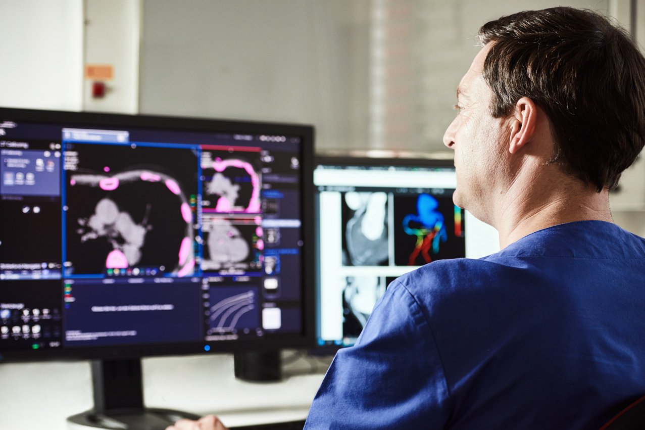 Ein Arzt an einem Monitor begutachtet die Computertomographie eines Herzens