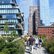 Mehr als Wolkenkratzer Menschen spazieren auf einem begrünten Fußweg zwischen modernen Hochhäusern und historischen Backsteingebäuden in im dicht bebauten New York.