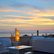Terrassenmöbel mit Stehleuchte vor Wasserlandschaft bei Sonnenuntergang