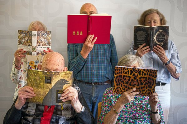 alte Menschen mit aufgeschlagenen Büchern vor dem Kopf
