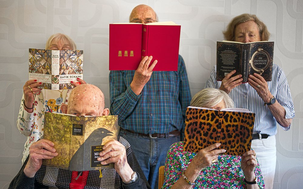 alte Menschen mit aufgeschlagenen Büchern vor dem Kopf