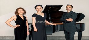 Klavierensemble; Musiker stehen vor einem Flügel