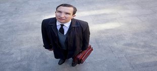 stehender Mann mit Tasche schaut nach oben