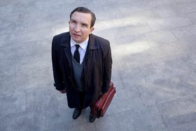 stehender Mann mit Tasche schaut nach oben