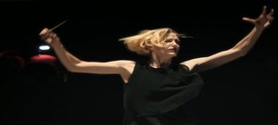 Blonde Frau in ausladender Dirigierbewegung