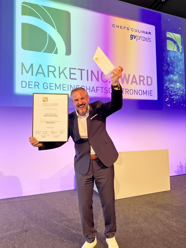 Christoph Specht freut sich auf der Bühne über die Auszeichnung mit dem Marketing Award der Gemeinschaftsgastronomie 2023