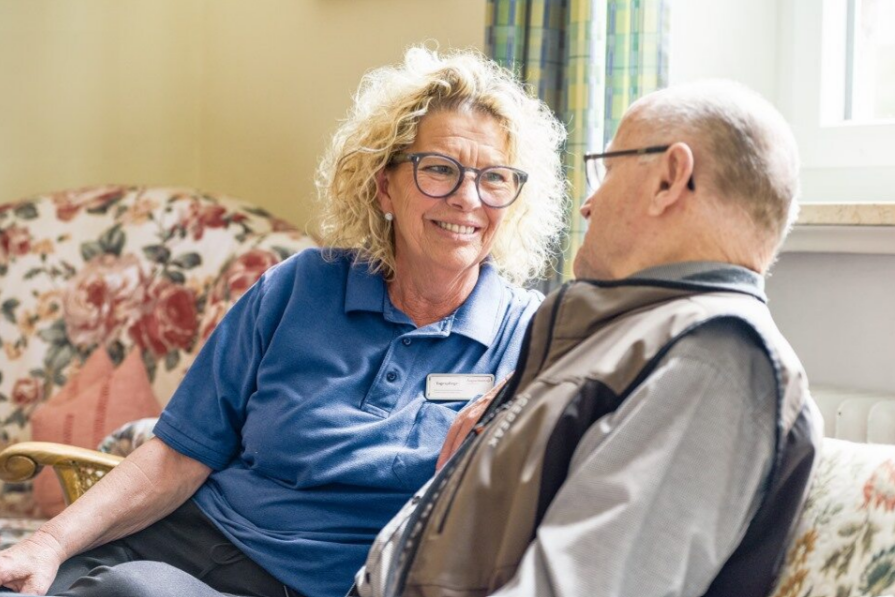 Eine Mitarbeiterin der Tagespflege im Austausch mit einem Bewohner