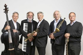 Fünf Musiker einer Jazz- und Swingband stehen nebeneinander und präsentieren ihre Instrumente: Kontrabass, Keyboard, Trompete, Saxophon und Gitarre.