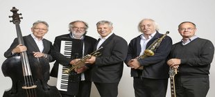 Fünf Musiker einer Jazz- und Swingband stehen nebeneinander und präsentieren ihre Instrumente: Kontrabass, Keyboard, Trompete, Saxophon und Gitarre.