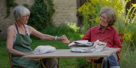 Akteurinnen am Tisch mit gereichten Händen